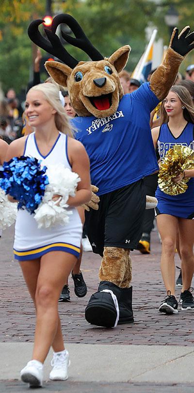 cheerleaders and the louie mascot walk during the homecoming parade